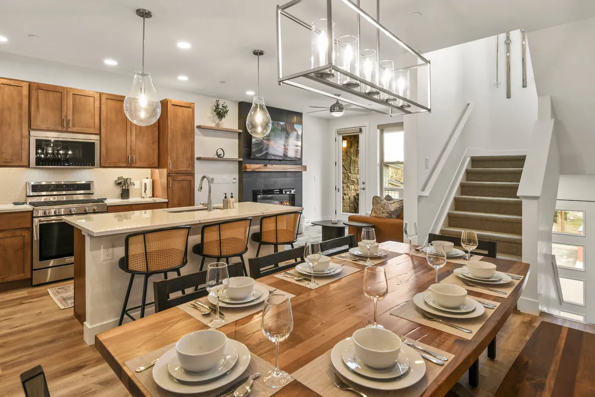 A modern, open-plan kitchen and dining area featuring a well-appointed kitchen island, elegant light fixtures, and a cozy fireplace. The space is bright and welcoming, designed to accommodate culinary adventures and celebratory gatherings.