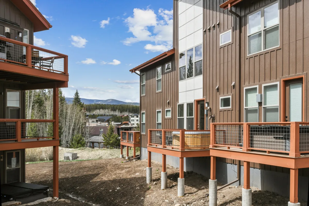 This image features the exterior of a modern chalet-style building with balconies overlooking a serene landscape. The surrounding scenery hints at mountain views, and the architectural design conveys privacy and sophistication.