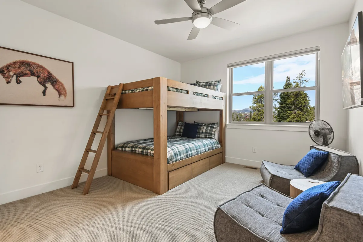 A playful and inviting bunk room with a full-over-full bunk bed, whimsical fox artwork, and cozy armchairs for reading or playing games. The room is bathed in natural light, making it ideal for kids or friends seeking a fun sleepover spot.