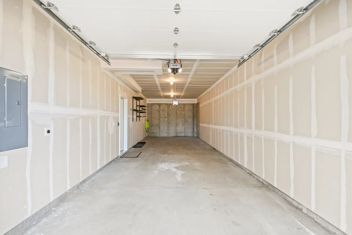 This image shows a tidy tandem garage with a visible garage door opener, concrete floor, shelving, and space for vehicles or gear. Its practical, organized layout highlights ample room for adventure equipment and secure vehicle storage.